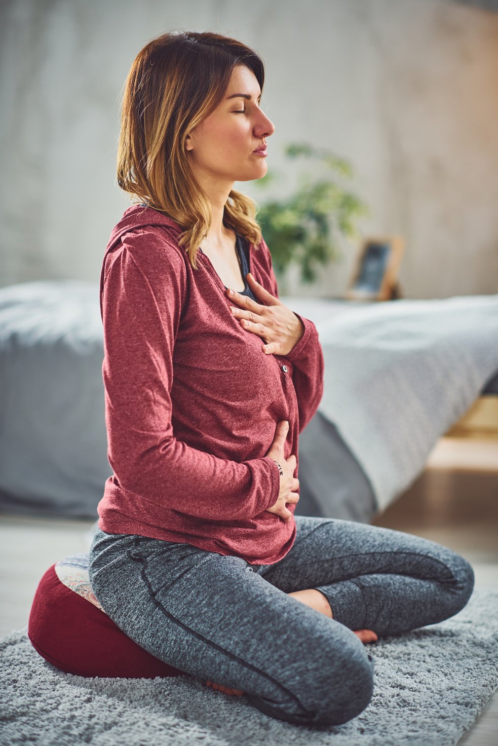 Woman practicing breathing in bedroom.